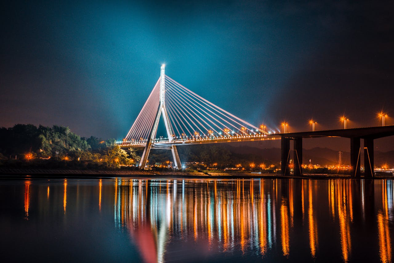A Budapest bridge illuminated at night with warm lights reflecting on the Danube
