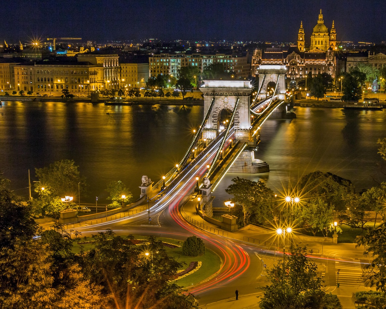 A Budapest bridge illuminated at night with colorful reflections on the Danube