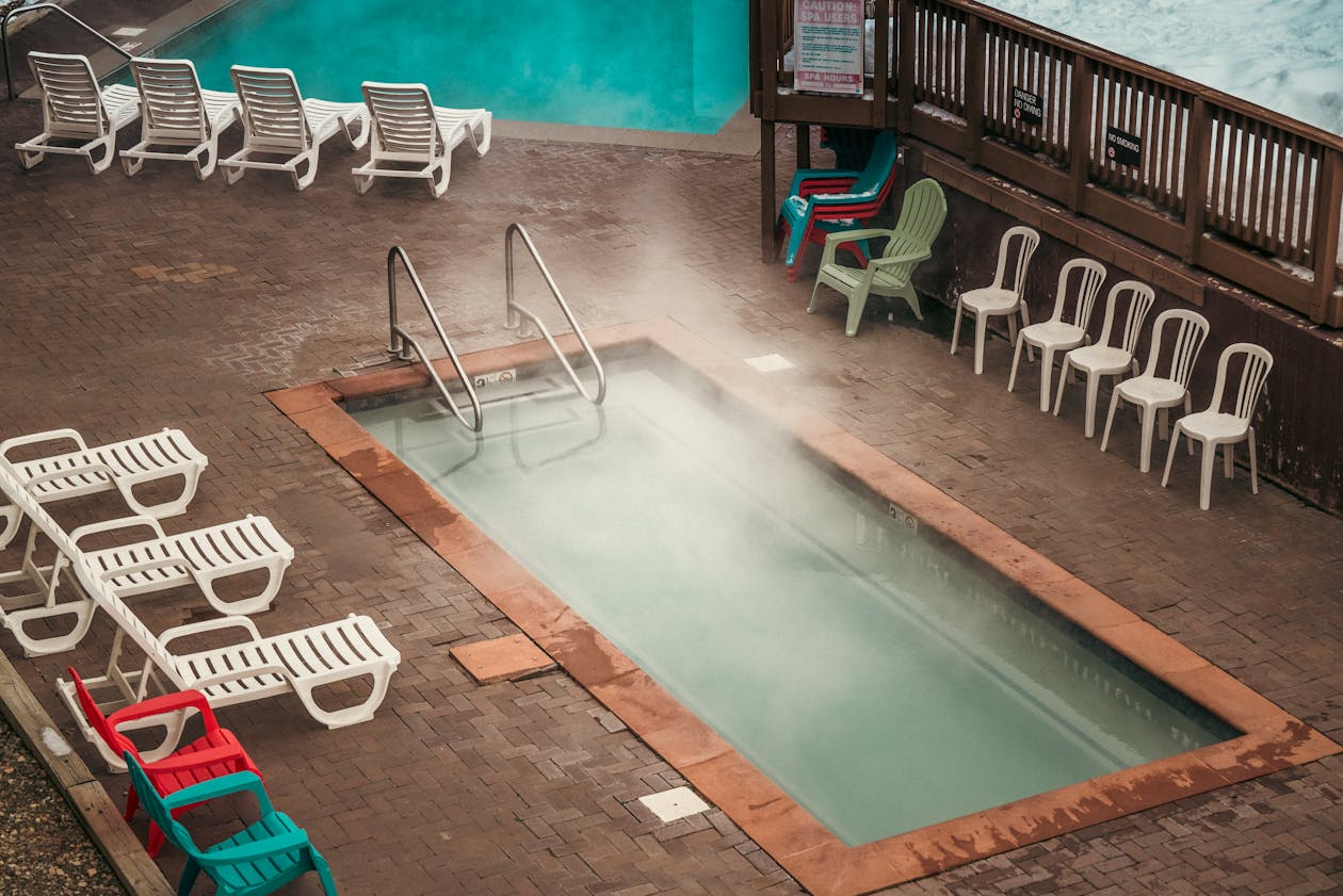 Aerial view of a steaming outdoor thermal pool with sunbeds