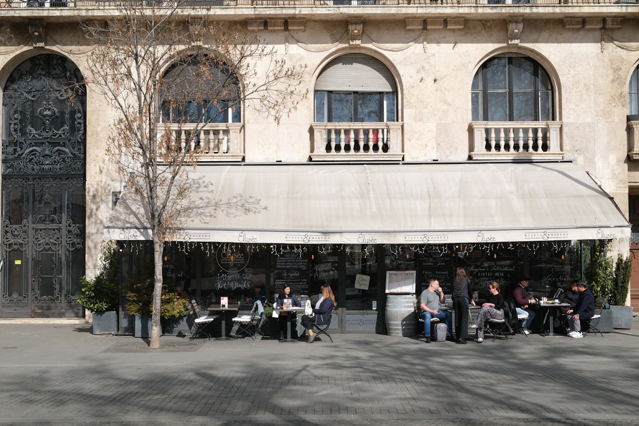 Patrons enjoying a sunny day at a charming street café in Budapest