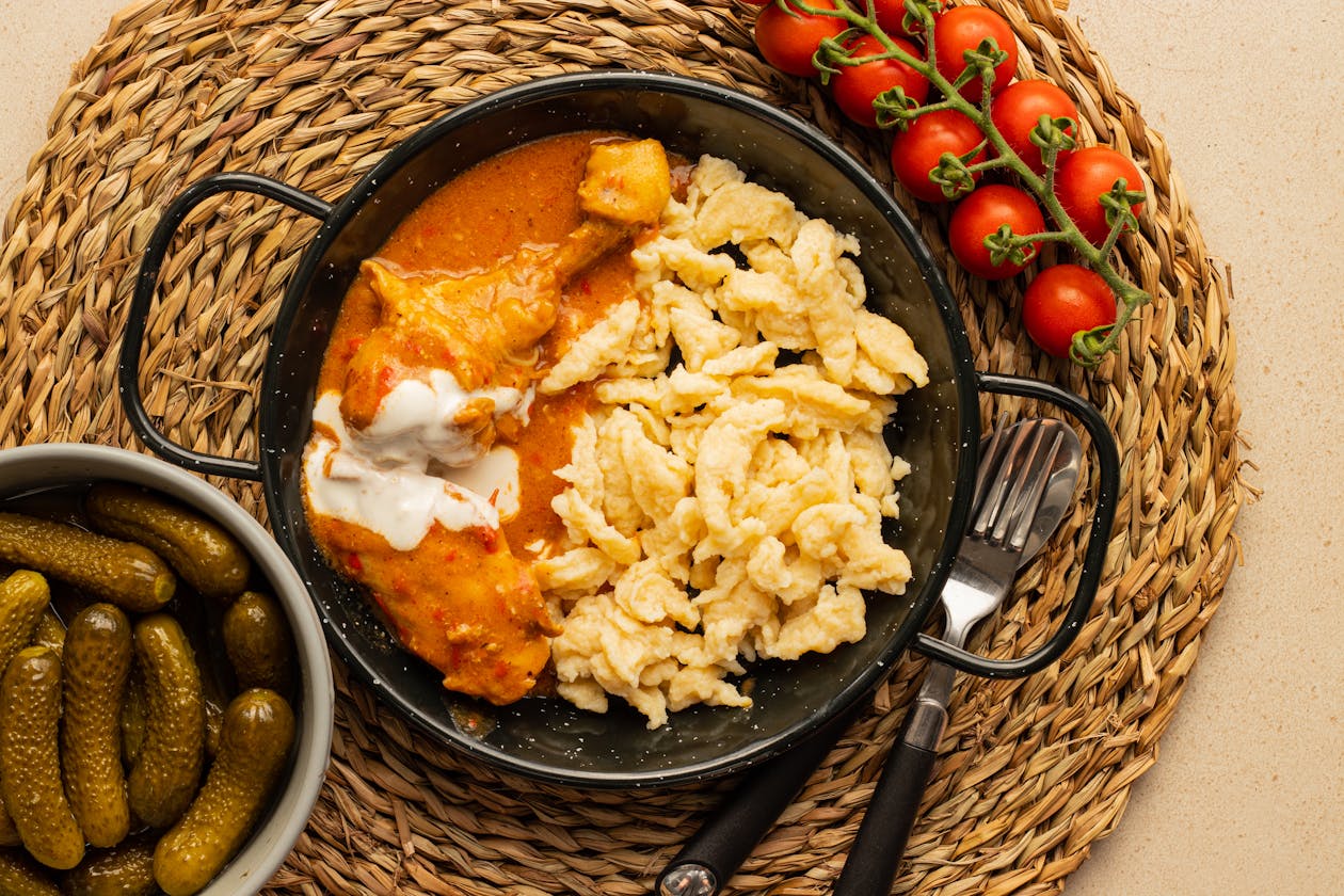 Traditional chicken paprikash served with spaetzle noodles and pickles