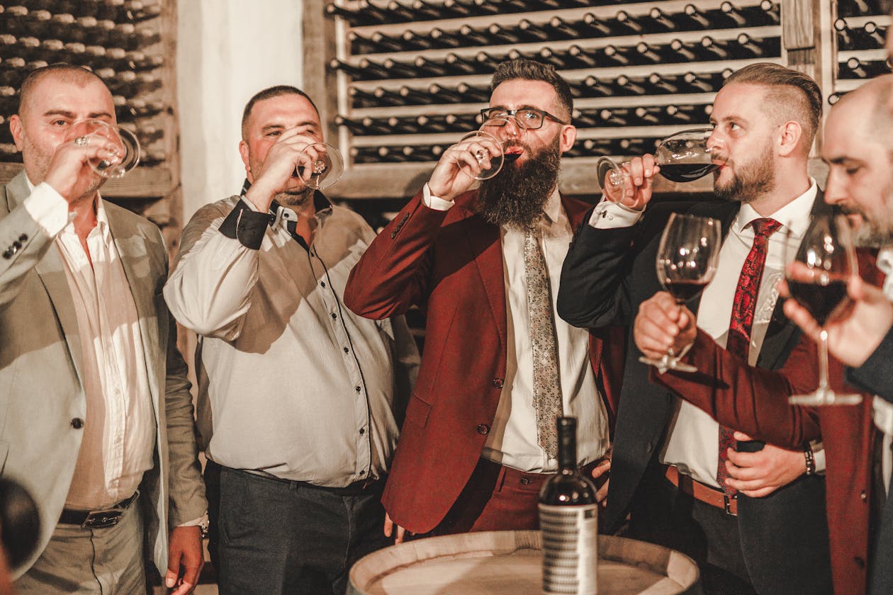 Group of men drinking wine at an indoor wine tasting gathering