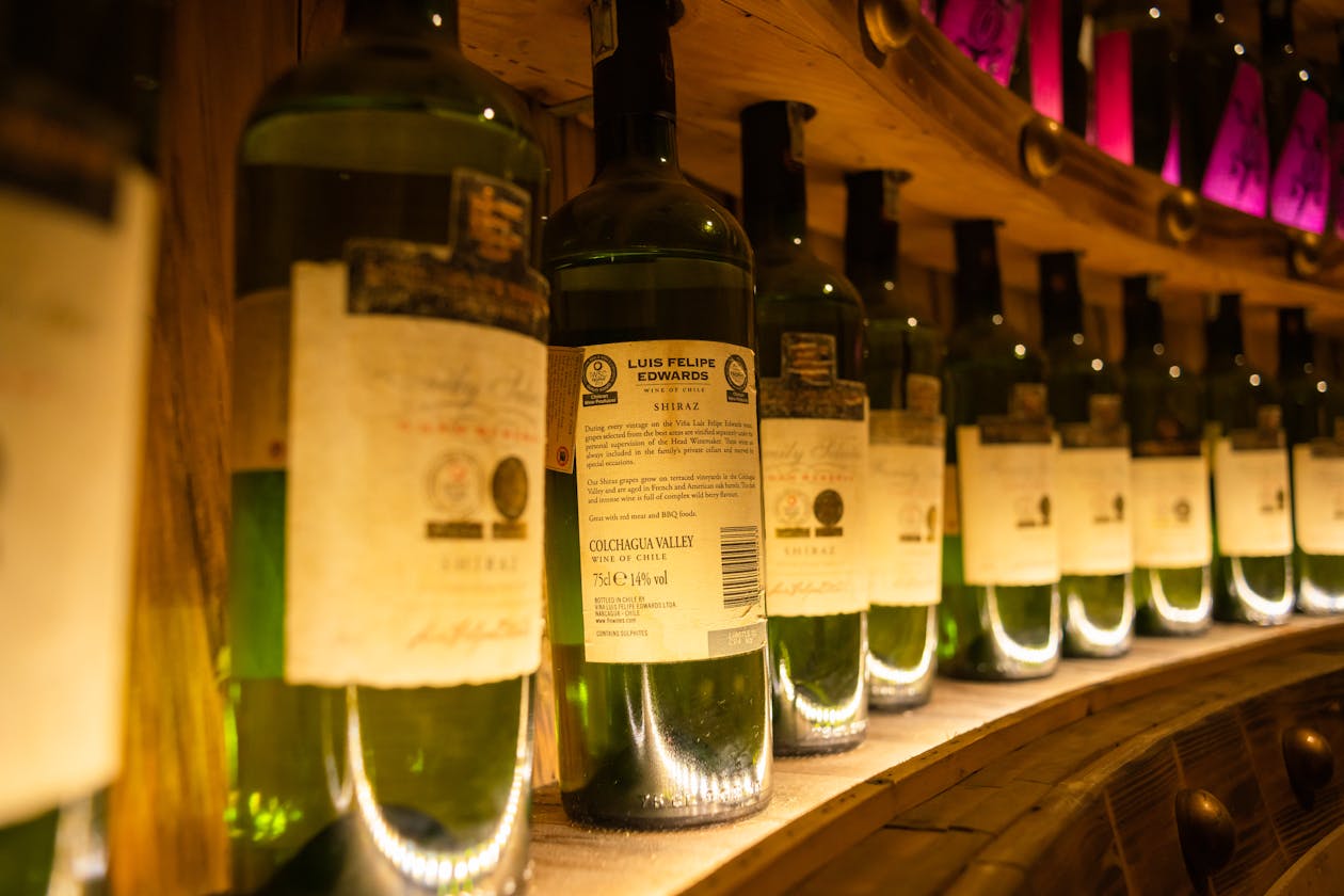 Row of wine bottles in a warmly lit wine cellar showing labels