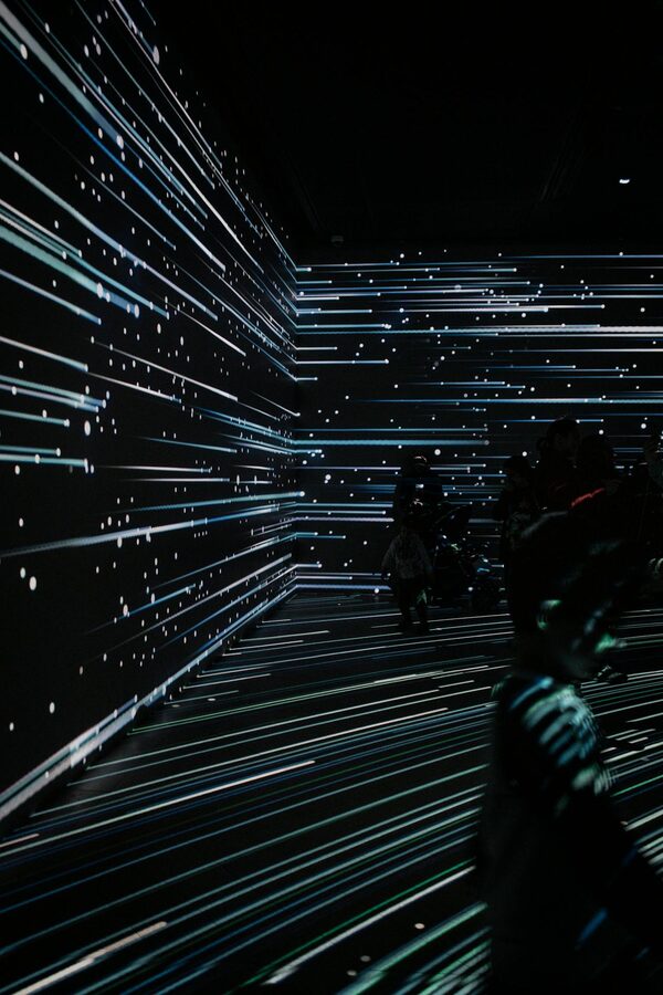 Abstract light installation with figures silhouetted against projecting lights