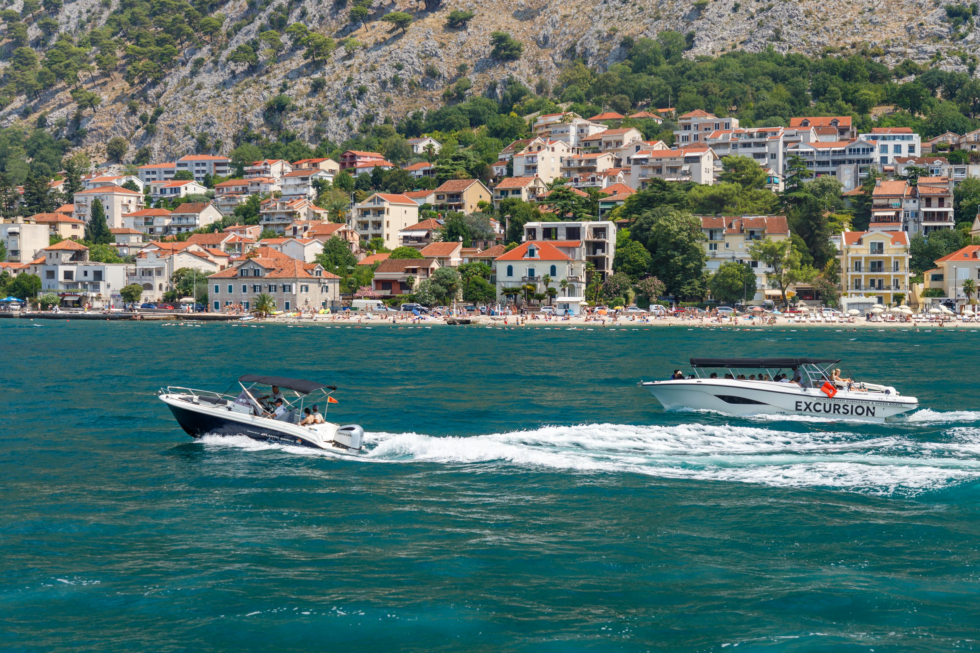 Two boats cruising along the Adriatic coast with a scenic coastal town backdrop