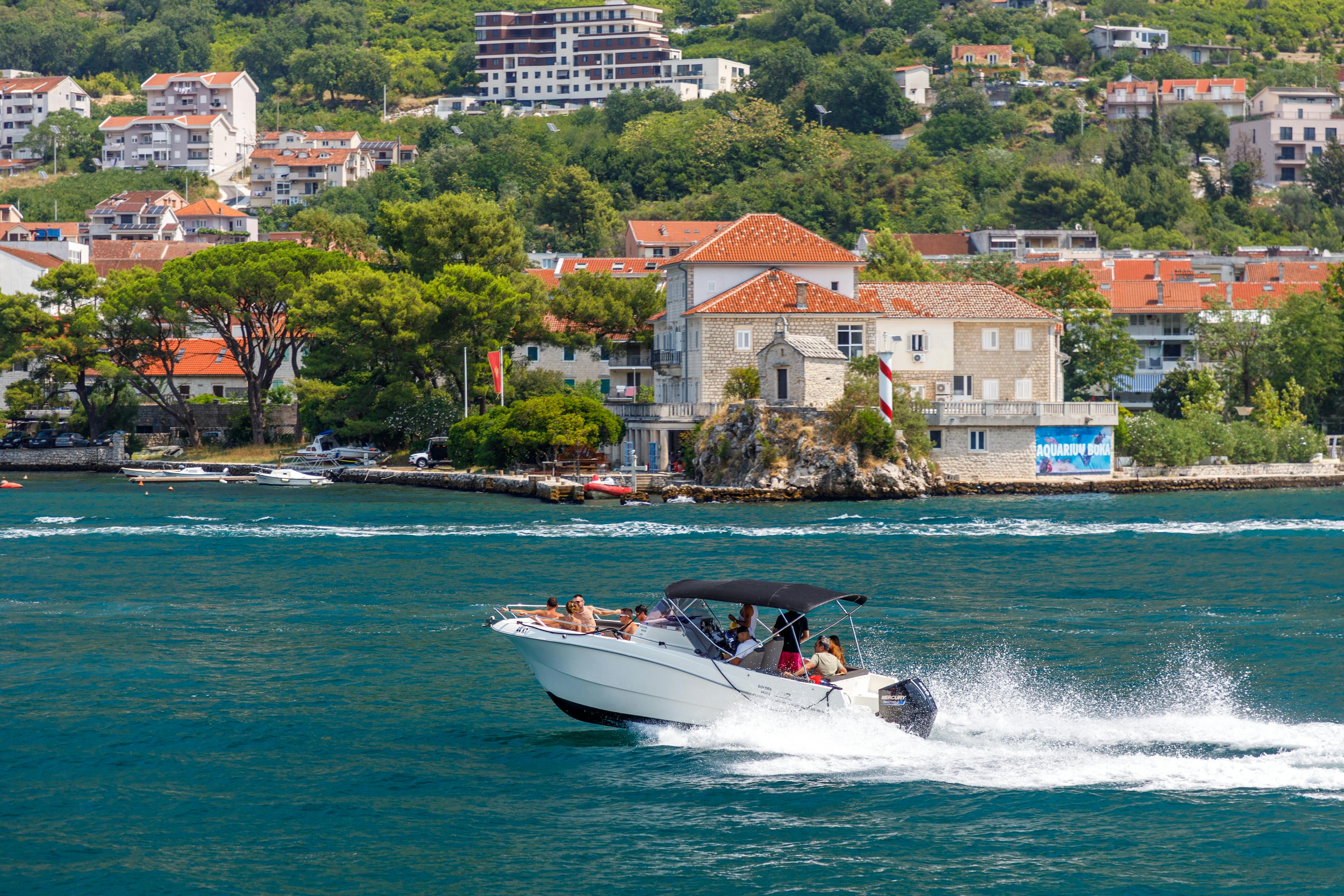 A speedboat races along the scenic Adriatic coast with hillside villas in the background