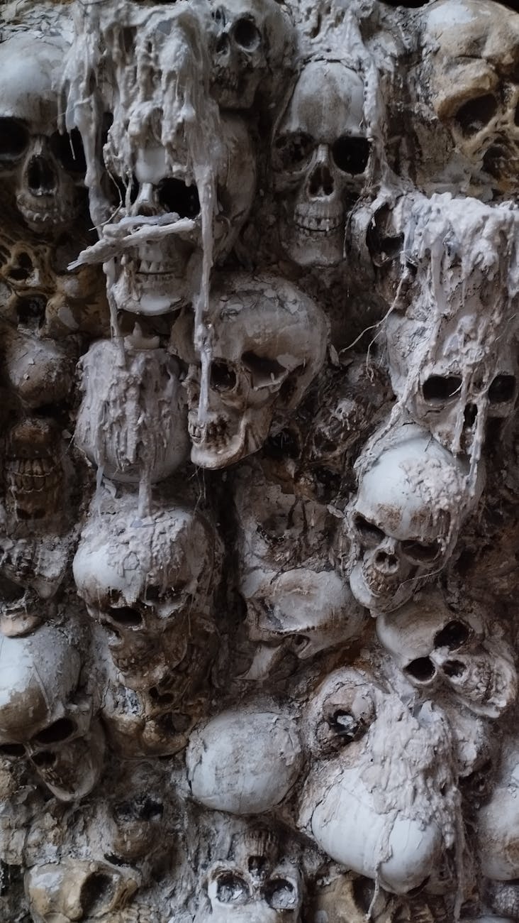 Aged human skulls stacked closely in a historical crypt