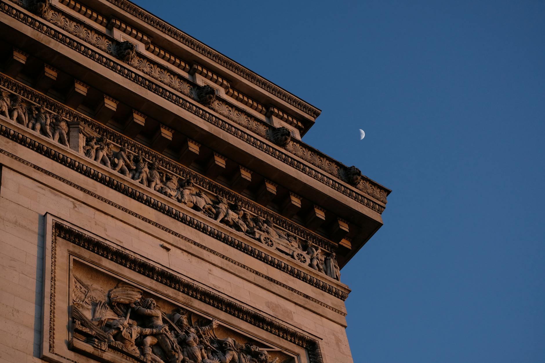 The Arc de Triomphe with a crescent moon at twilight