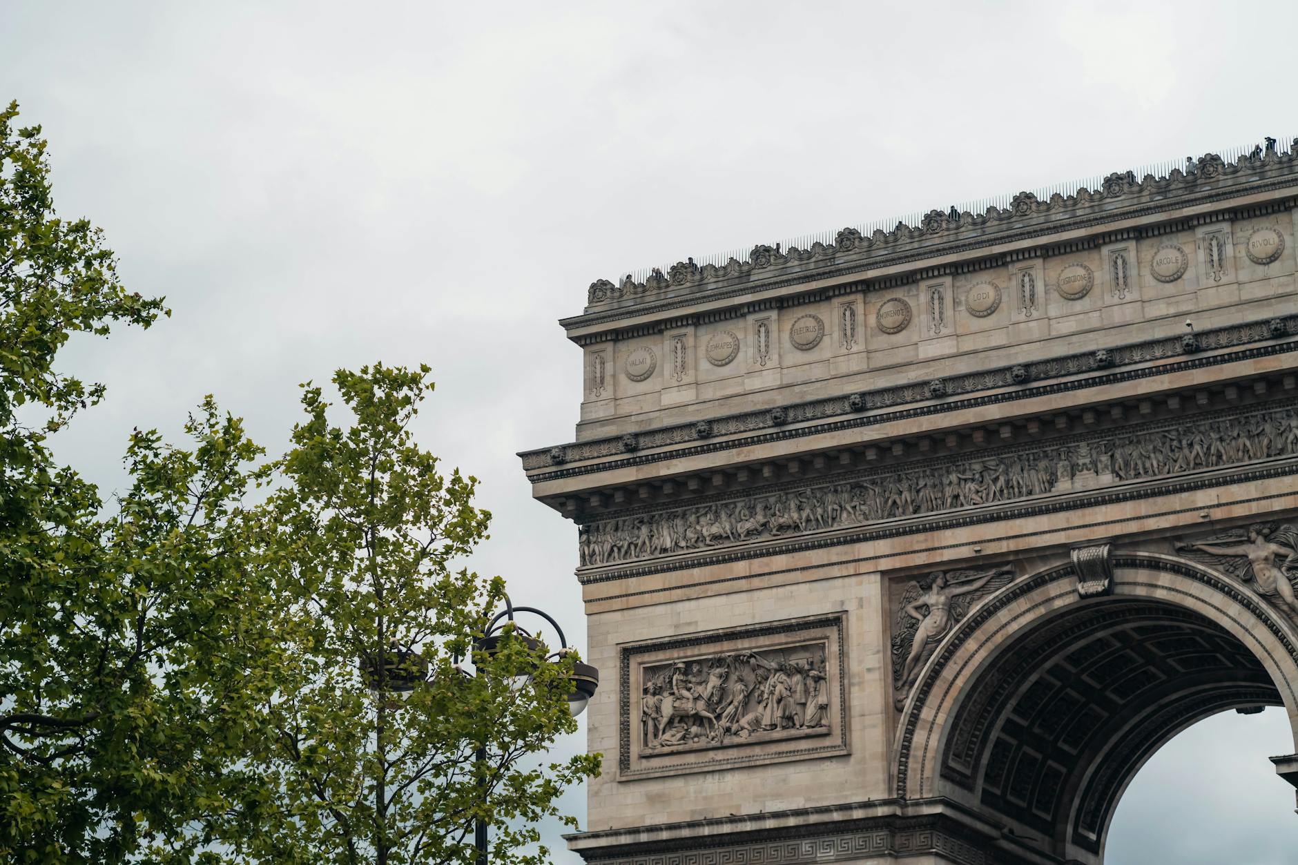 A partial view of the Arc de Triomphe with surrounding trees