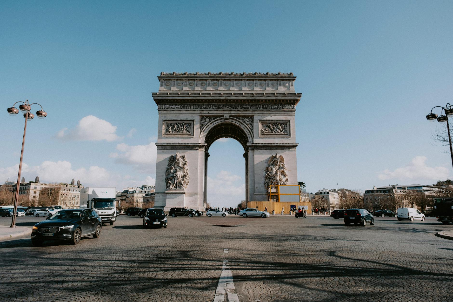 The historic Arc de Triomphe in Paris with cars on a sunny day