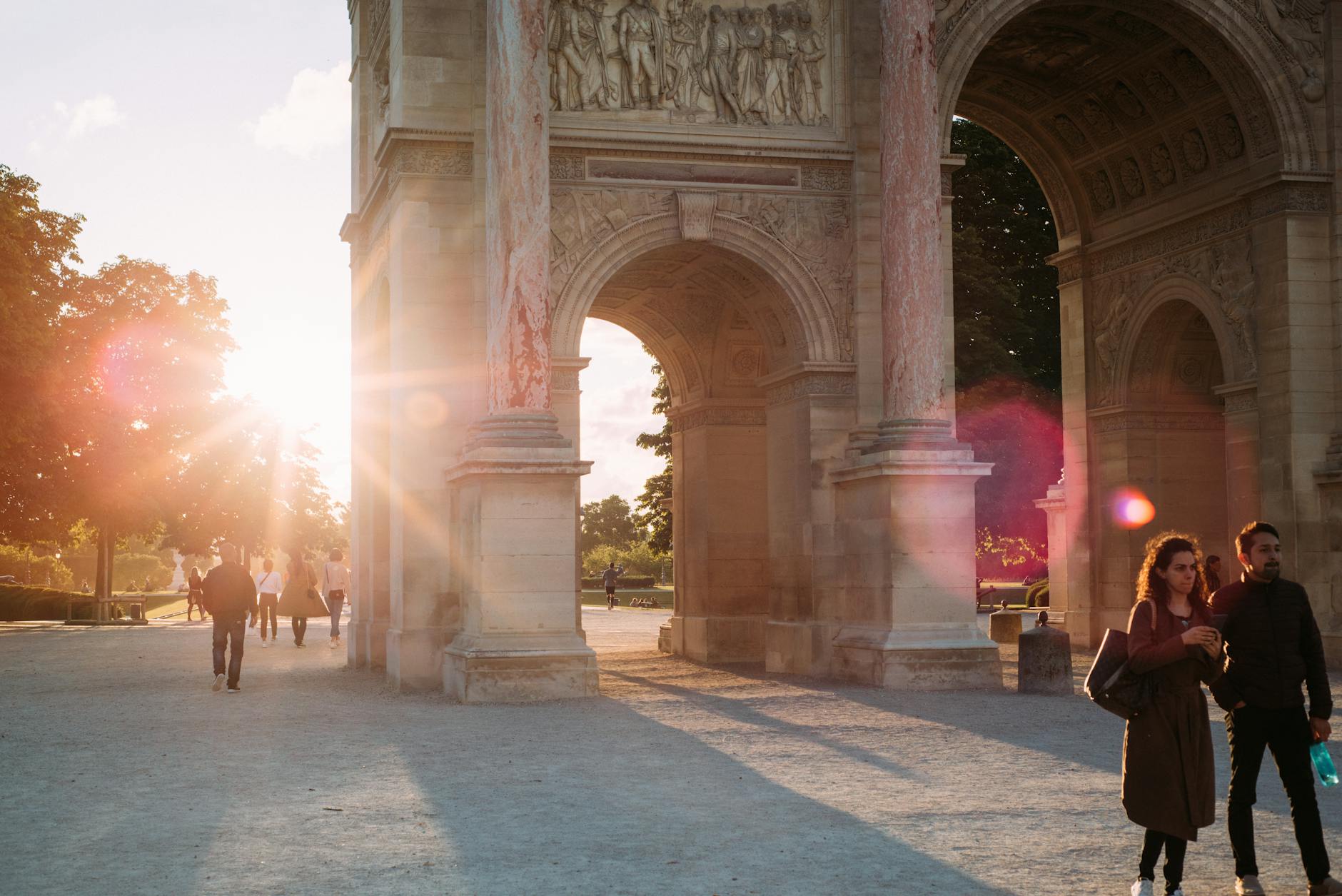 Sunrays through the Arc de Triomphe archway with people