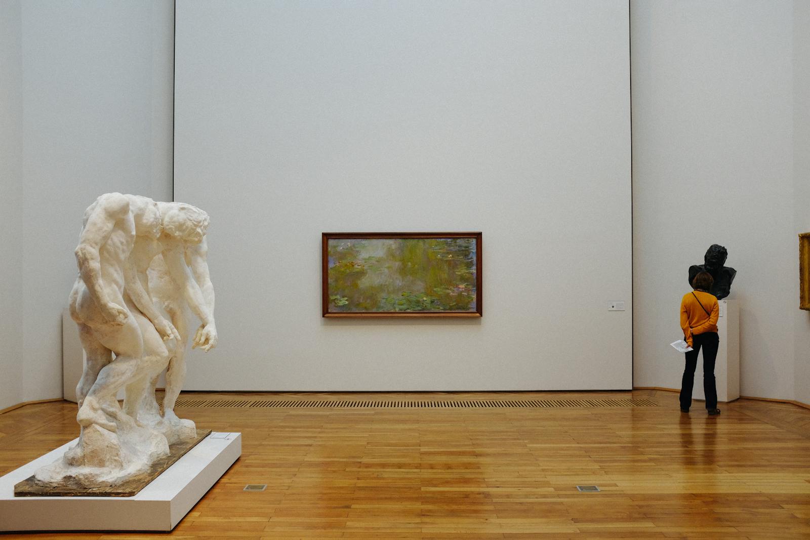 A visitor examines sculptures and paintings at an art museum