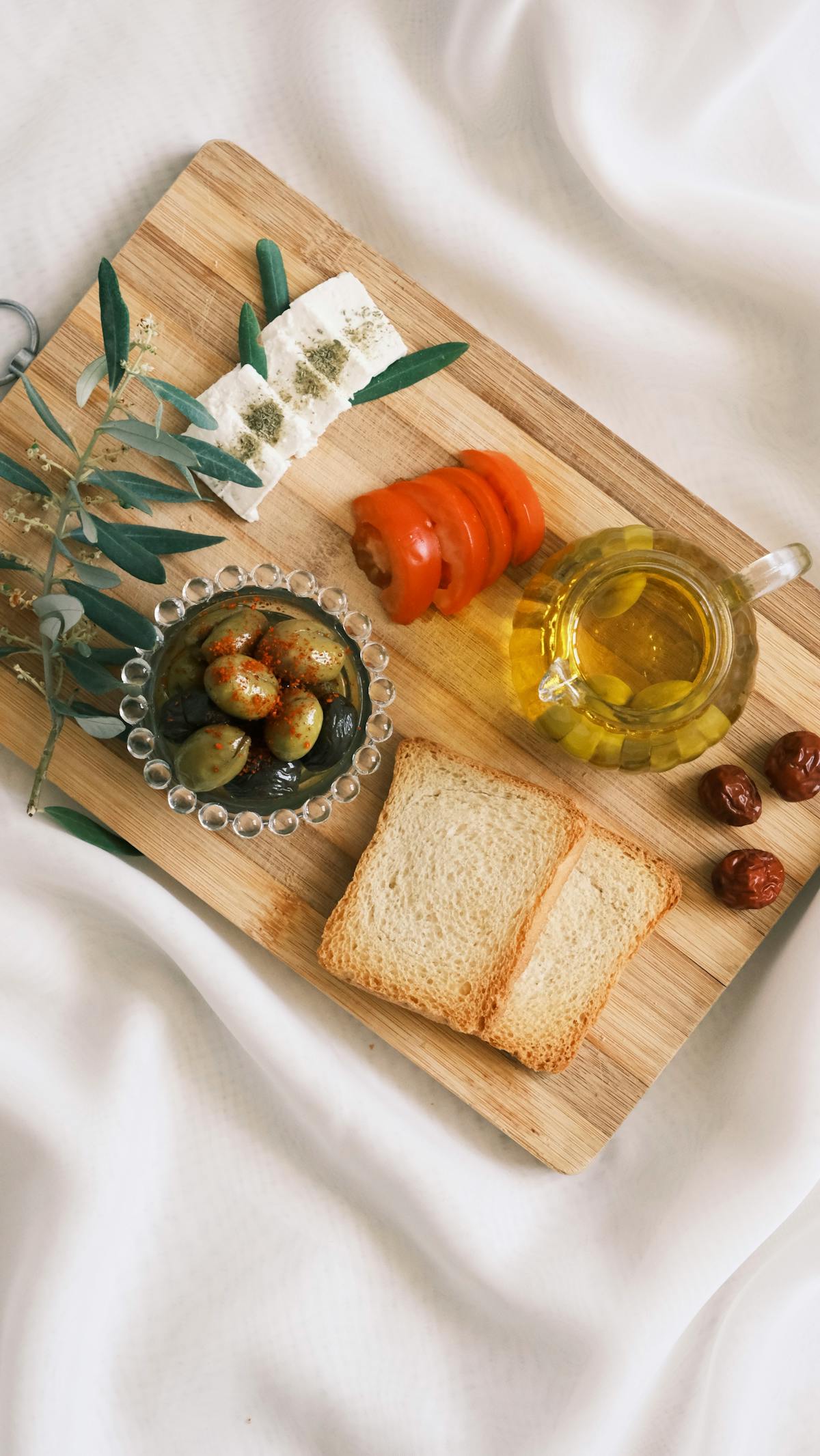 Mediterranean ingredients with bread, olives, and olive oil on a wooden tray