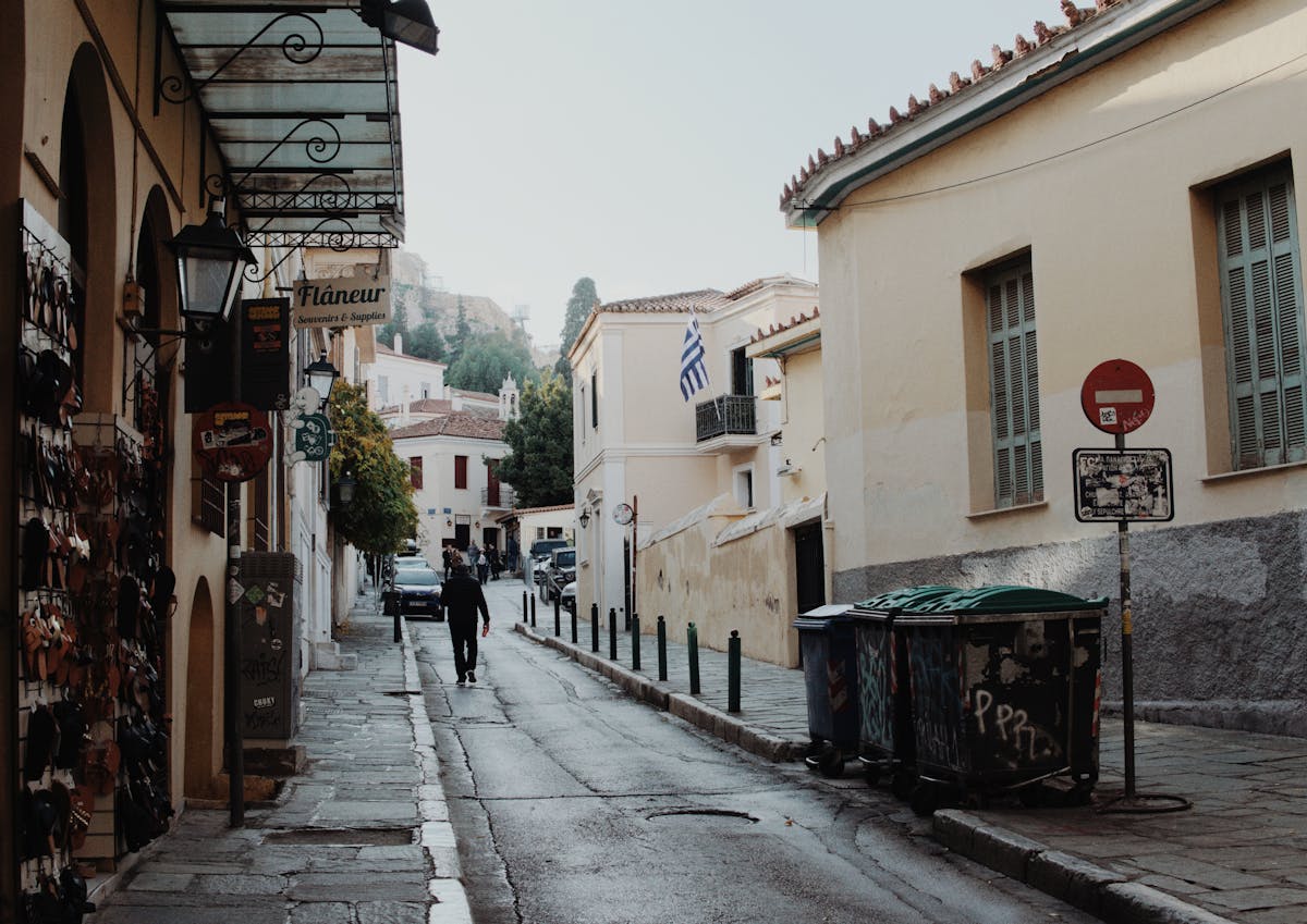 Quiet street in Athens' Plaka district with Greek flag and quaint shops