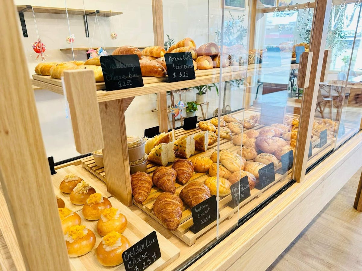 Bakery display case with rows of freshly baked pastries and bread