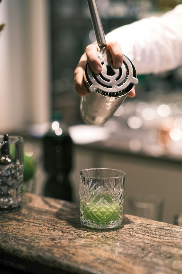 Bartender mixing a green cocktail at a bar in Paris