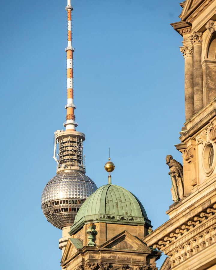 Berlin TV Tower next to historical architecture under blue sky