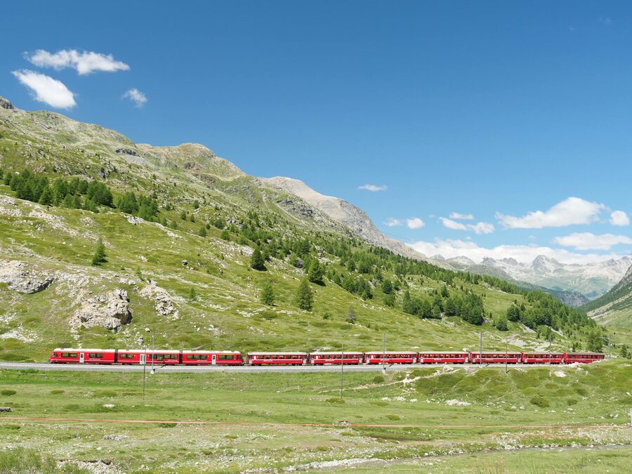 Red train traversing Bernina Pass Switzerland