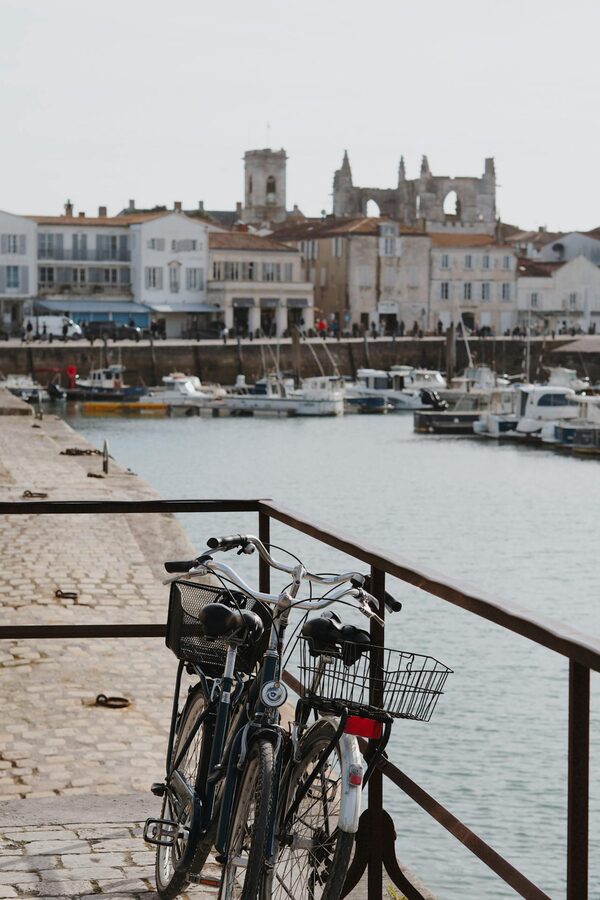 Bicycles parked by harbor railing with historic town and boats