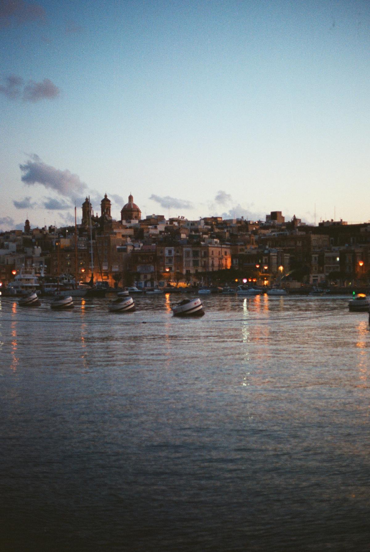 Birgu harbour at sunset with reflections on calm water