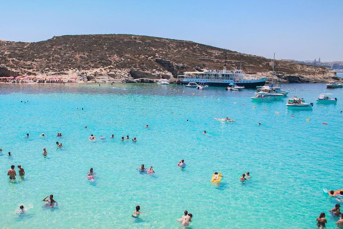 Swimmers and boats at Malta Blue Lagoon on a sunny summer day