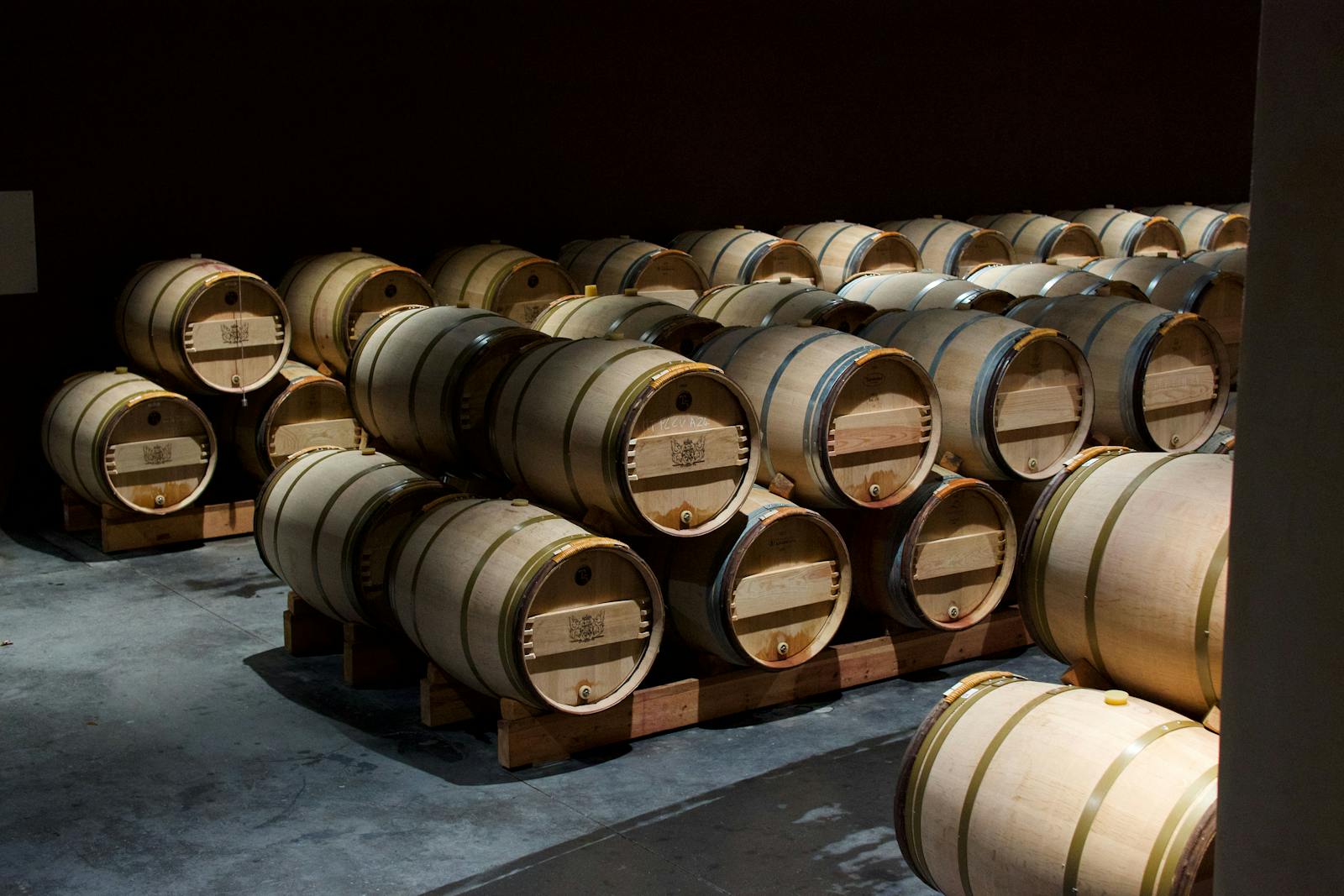 Stacked oak wine barrels in a dimly lit cellar in Pauillac France