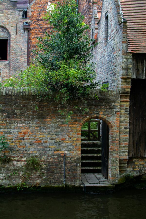 Brick archway leading to a charming courtyard in Bruges