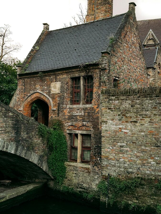 Brick house with archway in Bruges showcasing Gothic architecture