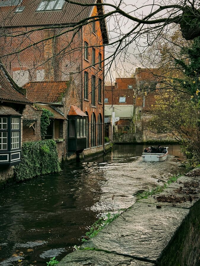 Bruges canal with boat and Flemish architecture in autumn