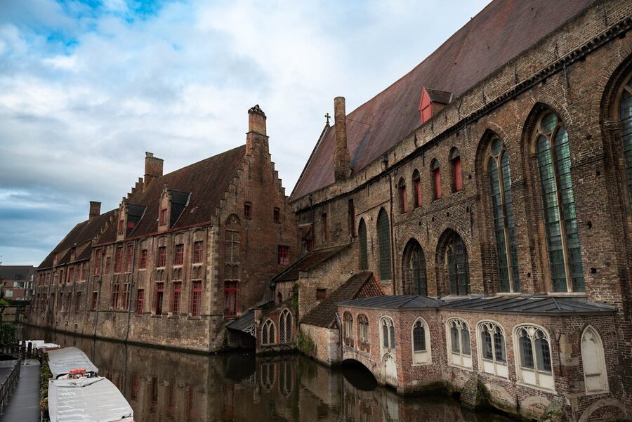 Historic brick buildings along a tranquil canal in Bruges Belgium