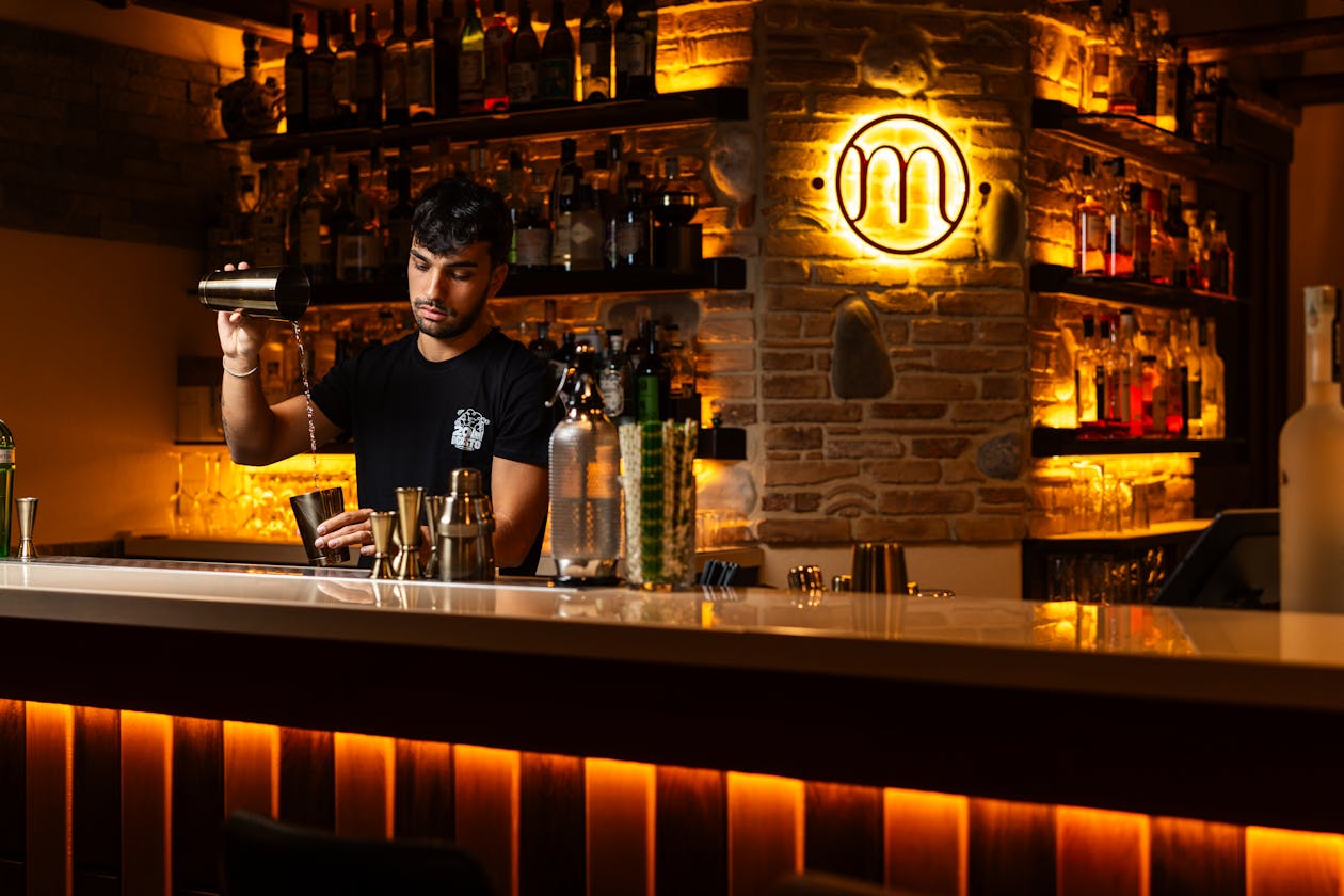 Bartender mixing cocktails at a dimly lit bar