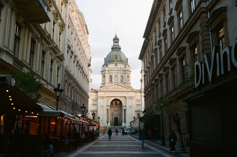A bustling Budapest street with pedestrians walking toward St Stephens Basilica