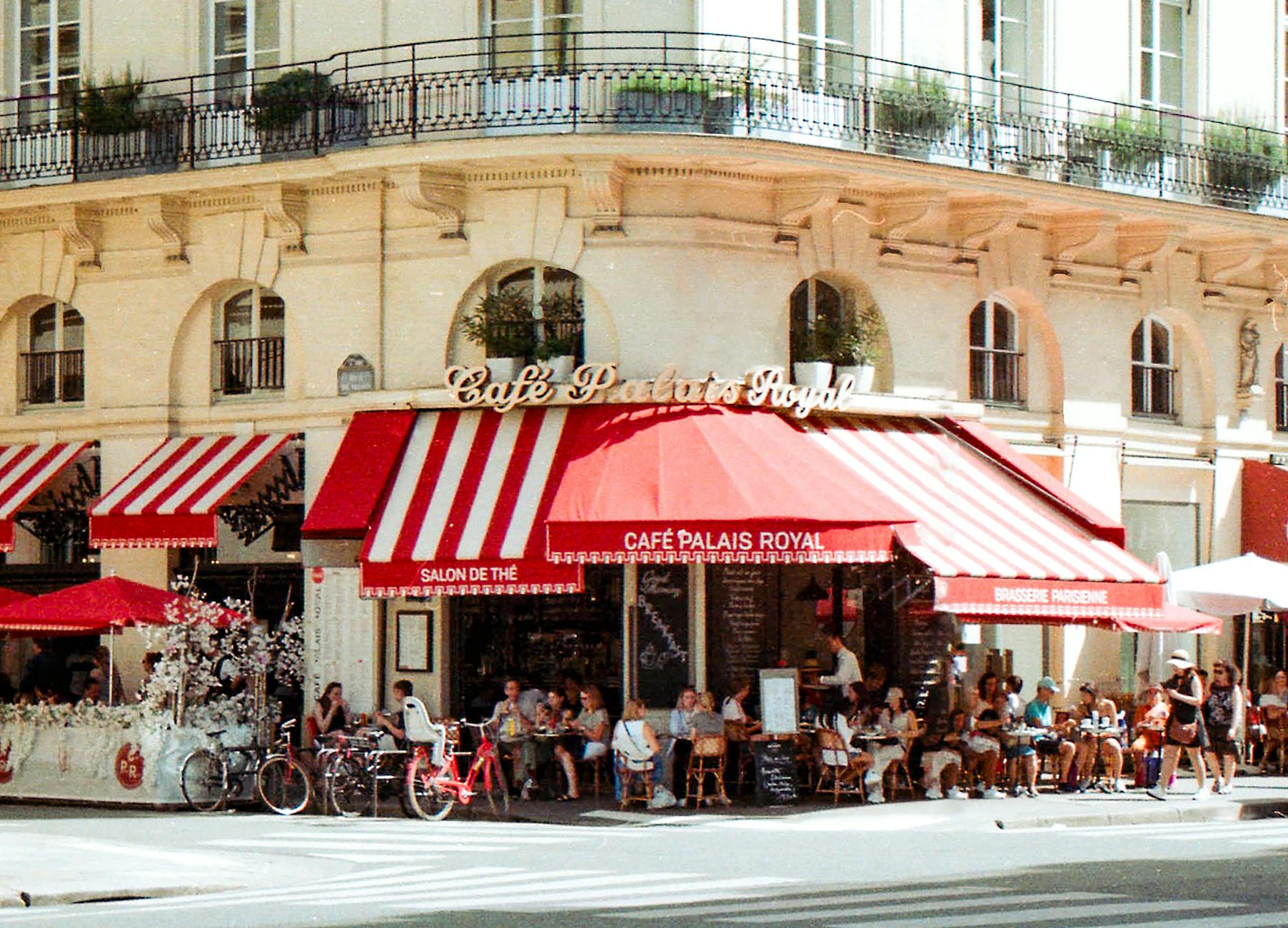 Parisian café scene with patrons enjoying a sunny day near Palais Royal