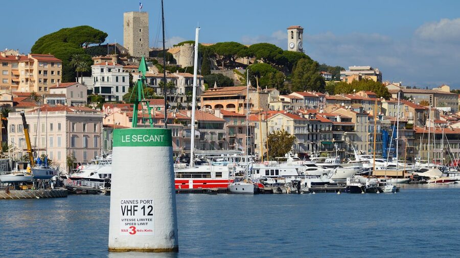 Cannes harbor with luxury yachts and historic architecture on a sunny day