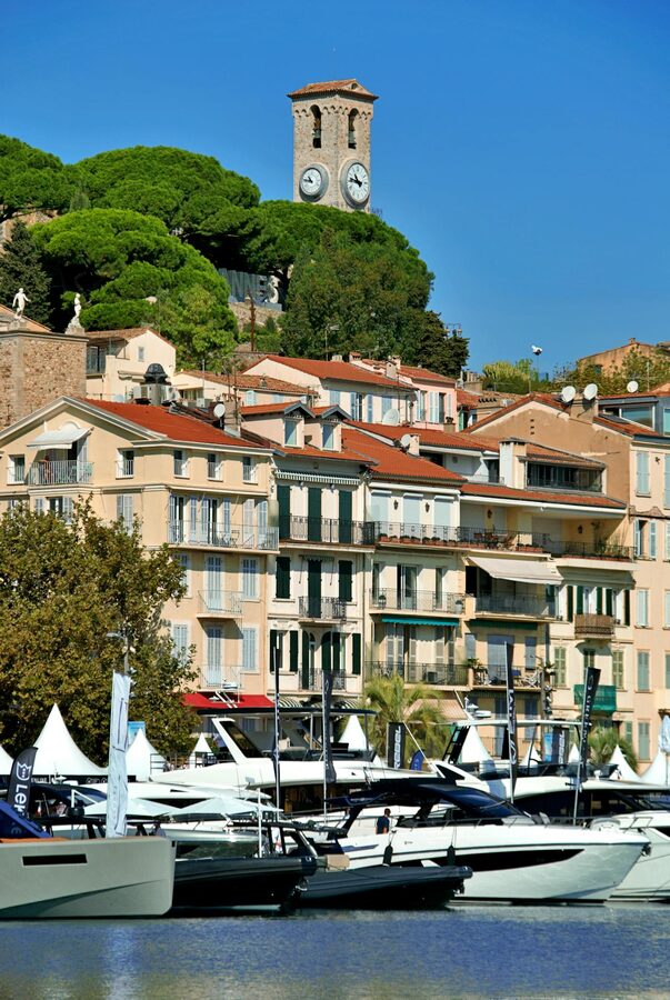 Luxury yachts docked at Cannes marina with clock tower