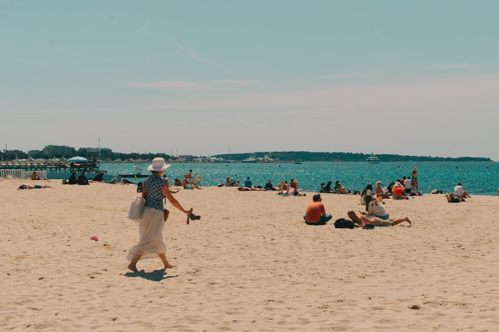 People enjoying a sunny day at a sandy beach in Cannes, France