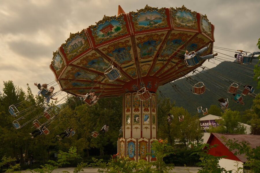 Colourful carousel swing ride outdoors with joyful riders at an amusement park