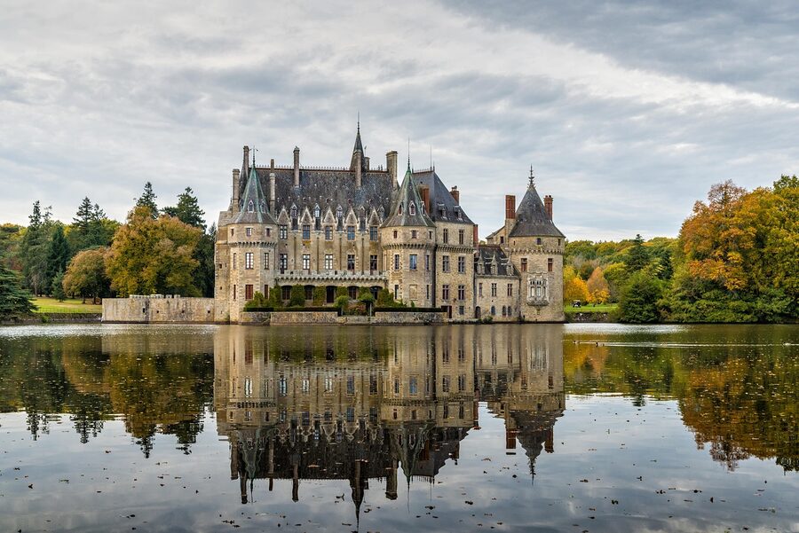 Castle with tower reflected in lake in France