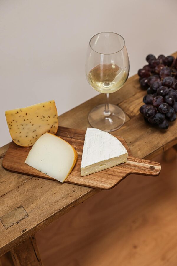 Cheese board with assorted cheeses grapes and white wine on rustic table