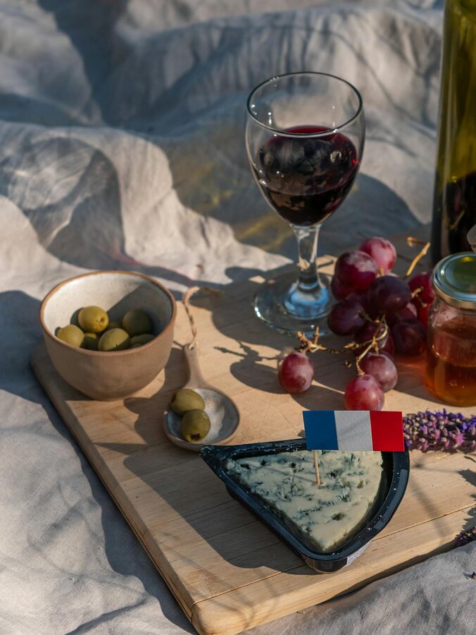 Cheese grapes olives and wine served on a wooden tray