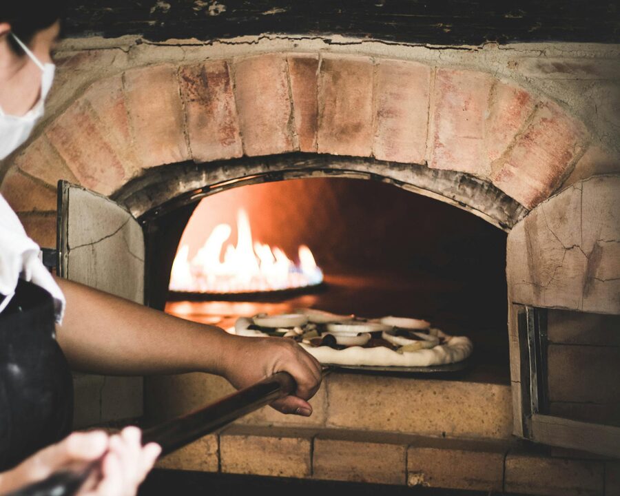 Chef placing pizza into a wood-fired oven