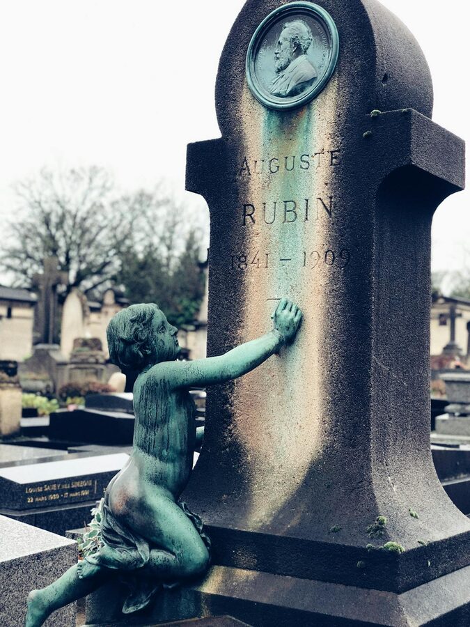 Detailed cherub sculpture adorning a headstone in a Parisian cemetery