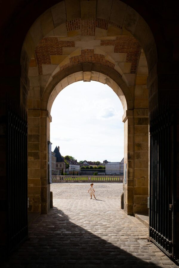 Child playing under archway at Chateau de Fontainebleau