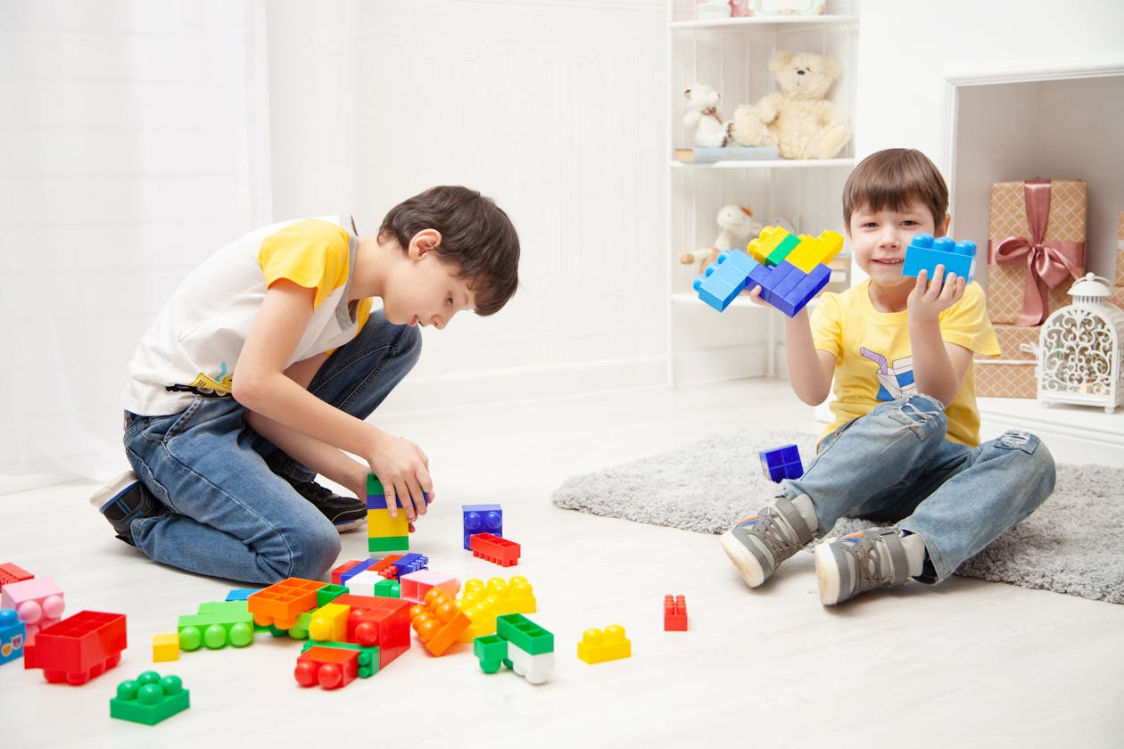 Two boys joyfully playing with colourful LEGO building blocks in a bright room