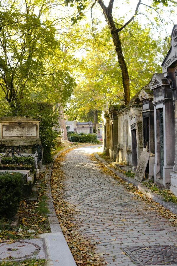 Cobblestone pathway surrounded by colourful fall trees in Pere Lachaise Cemetery