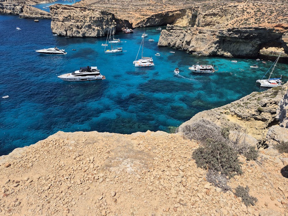 Boats anchored in crystal clear waters near Comino