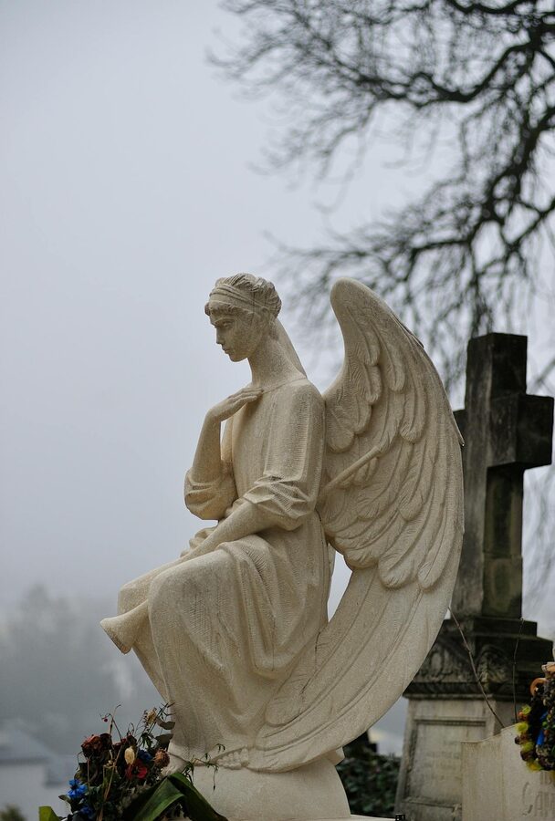 Angel statue in a misty cemetery setting with soft grey light