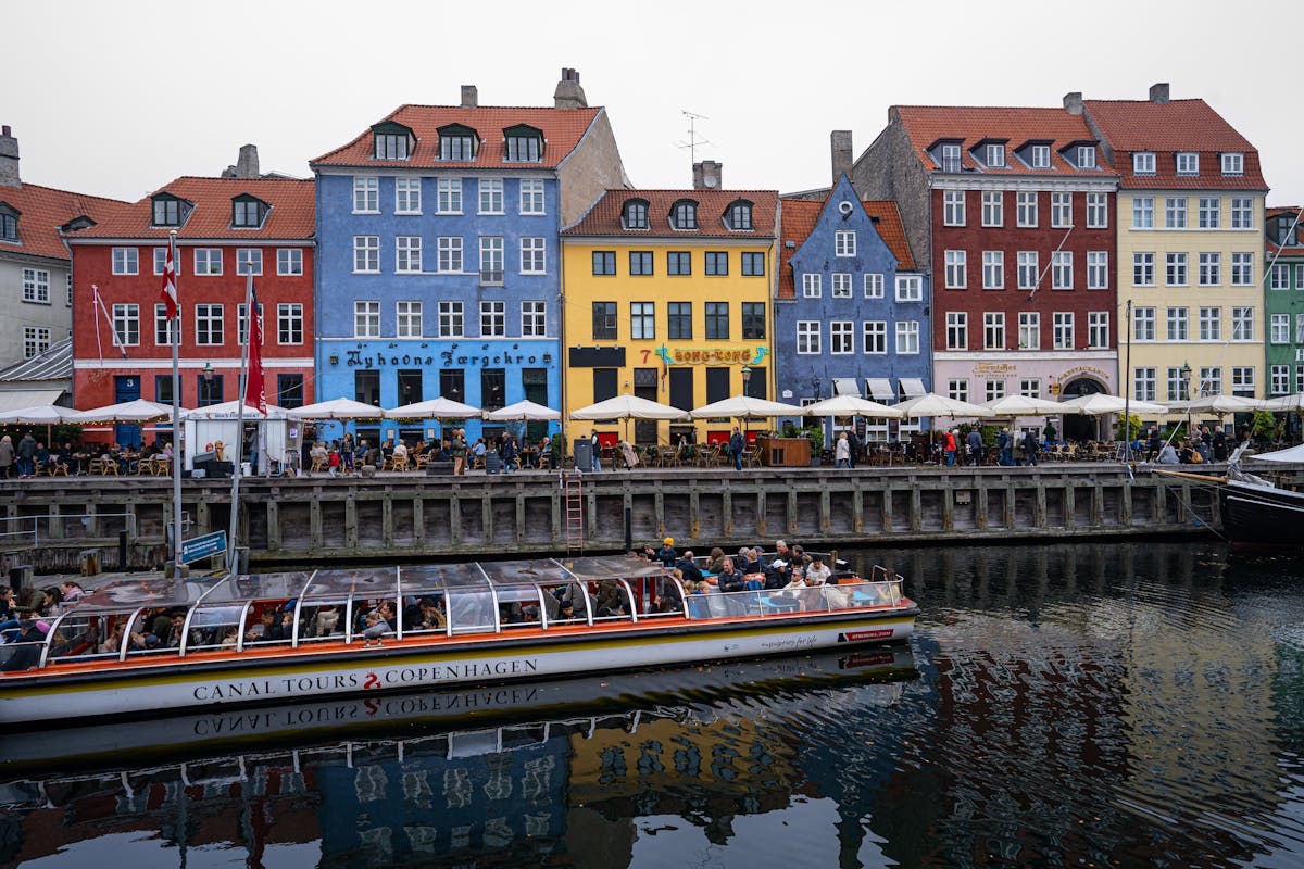 Canal tour boat passing colourful Nyhavn buildings in Copenhagen