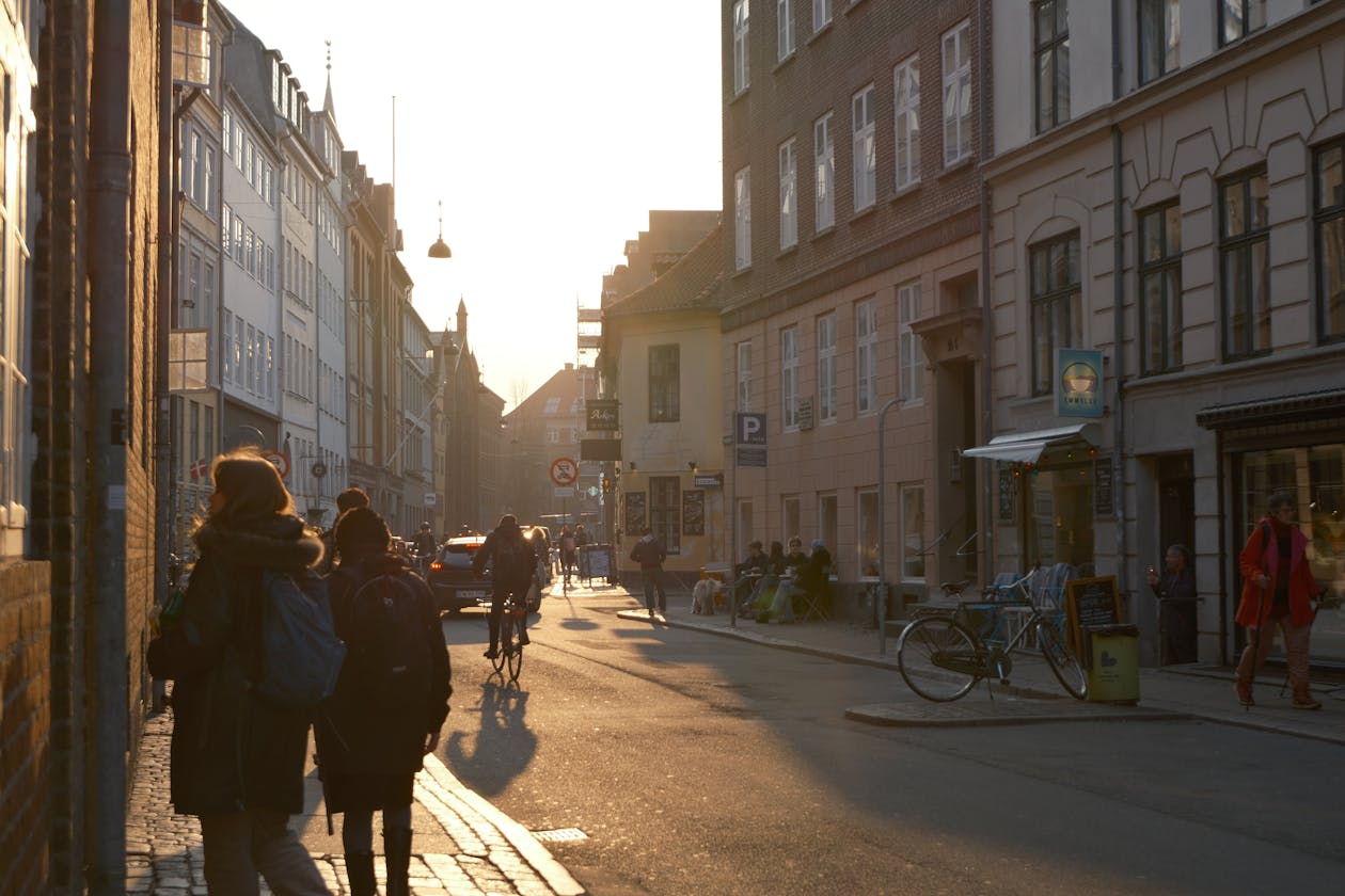 Sunlit street scene in Copenhagen with people and a cyclist capturing daily city life