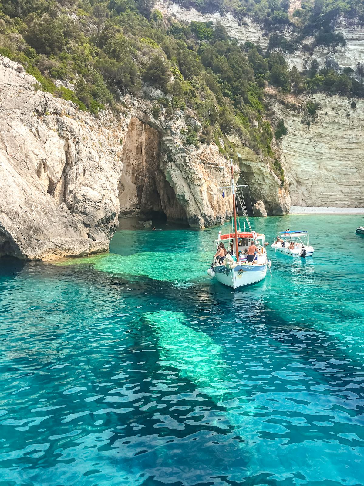 Tourists on boat near rock formations in clear water